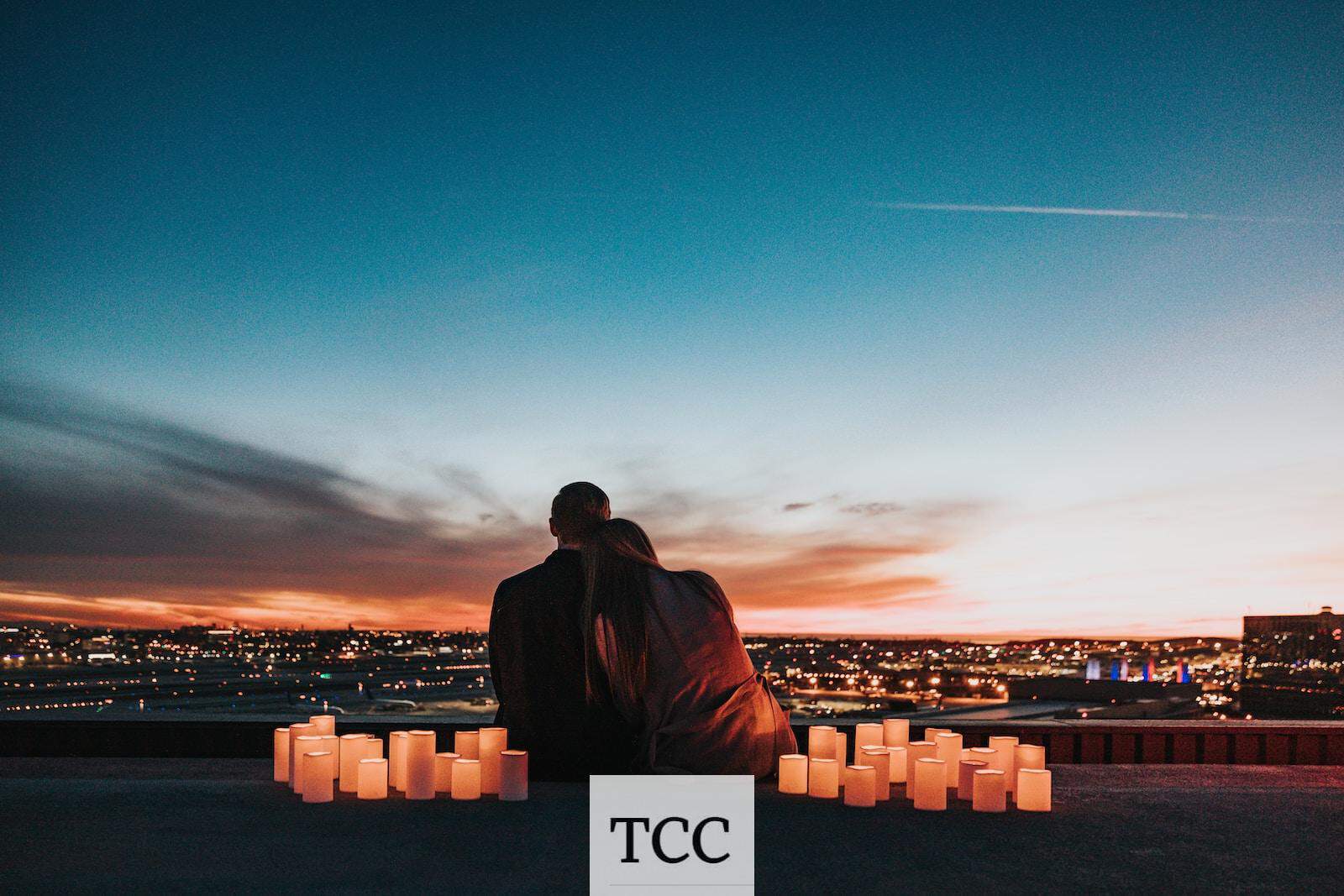 couple sitting on the field facing the city