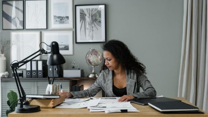Photo by Tima Miroshnichenko Businesswoman evaluates documents at a modern desk in a stylish office setting.