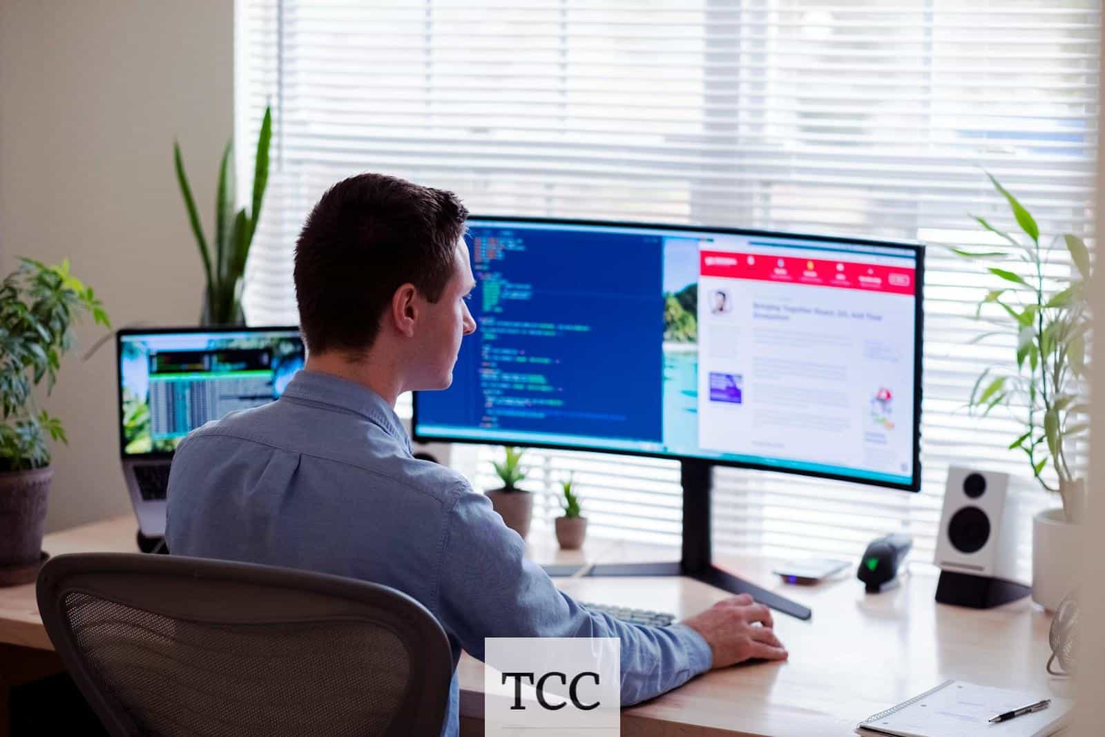 man in gray dress shirt sitting on chair in front of computer monitor